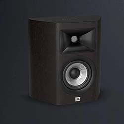 A modern home entertainment setup with a wall-mounted TV on an orange wall, a sleek wooden media console, a black stereo, and a tall speaker.