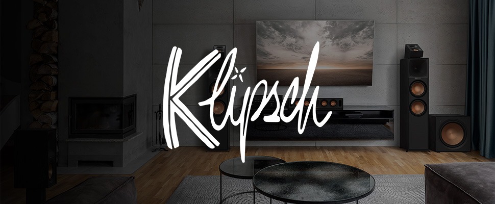Living room with modern Klipsch audio system. Large speakers with copper cones flank a TV, creating a sleek and sophisticated atmosphere.