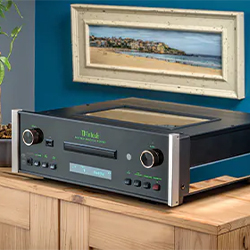 Vintage audio player on a wooden cabinet against a blue wall, with a coastal painting above. The scene conveys a classic, serene ambiance.