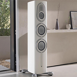 Tall, white floor-standing speaker with three circular drivers in a modern room setting, conveying a sleek and sophisticated audio experience.