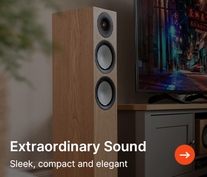 Sleek wooden speaker with three circular drivers beside a TV in a modern living room. Text reads "Extraordinary Sound, Sleek, compact and elegant."