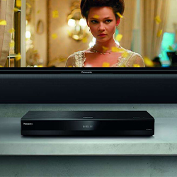 A Panasonic Blu-ray player sits below a TV showing a woman in a vintage dress. The setup suggests a home entertainment system. Mood is elegant and immersive.