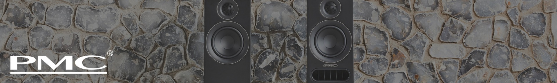 Two black PMC speakers stand on a stone wall background, showcasing sleek design and high-quality construction. PMC logo is visible on the left.