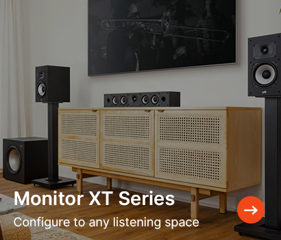 A modern living room features a stereo setup with speakers on stands, a wooden media console, and a wall-mounted TV. Text reads "Monitor XT Series. Configure to any listening space."