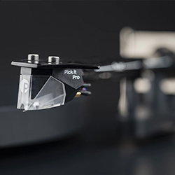 Close-up of a turntable cartridge labelled "Pick it Pro" against a blurred, dark background. The sleek design conveys a modern, sophisticated tone.