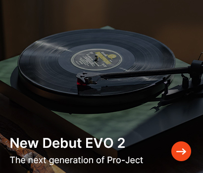 Vinyl record playing on a sleek black turntable with text reading "New Debut EVO 2 - The next generation of Pro-Ject." Mood is modern and nostalgic.