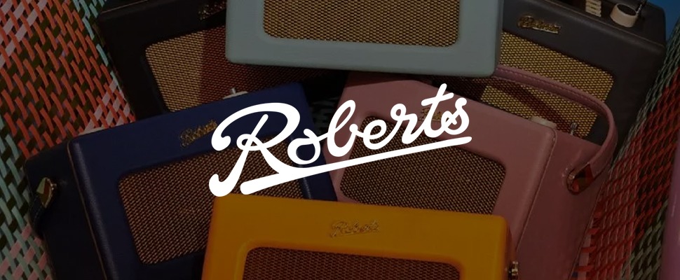 Colorful retro radios with mesh fronts are arranged in a pink basket. The brand name "Roberts" appears across several radios, exuding a vintage charm.