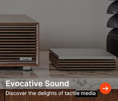 Wooden speaker and media player on a marble surface convey a retro, stylish vibe. Text reads "Evocative Sound: Discover the delights of tactile media."