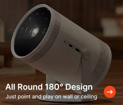 A modern white cylindrical projector with adjustable stand is angled upward in a cozy room. Text reads "All Round 180° Design, Just point and play on wall or ceiling."