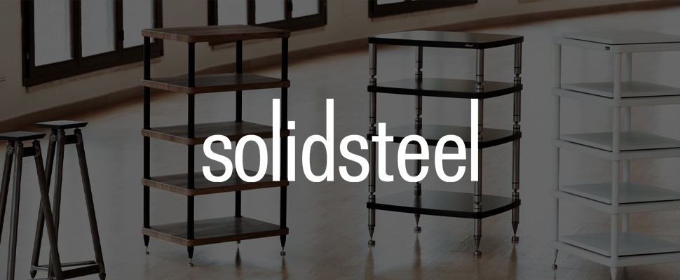 Modern audio racks in black, wood, and white are displayed against a light background. The word "solidsteel" in bold white is on the left, exuding sleek sophistication.