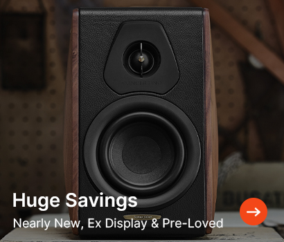 A black and brown speaker is centred, surrounded by a blurred workshop backdrop. Text in the foreground reads, "Huge Savings, Nearly New, Ex Display & Pre-Loved."