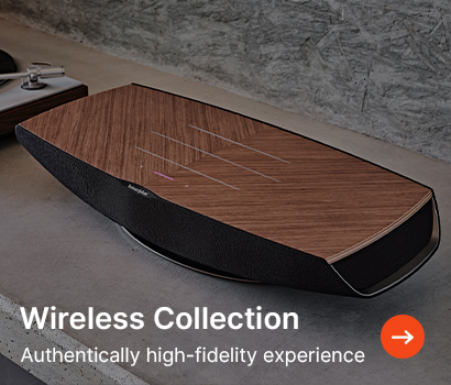 A sleek wireless speaker with a wooden finish on a concrete surface. Text reads "Wireless Collection: Authentically high-fidelity experience" with an arrow icon.