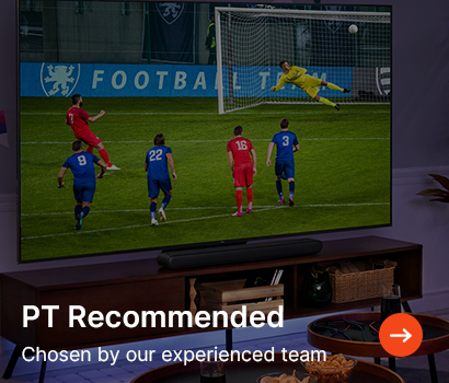 A soccer player in red takes a penalty shot as the goalkeeper in yellow dives to the right. The TV screen is labeled "PT Recommended."