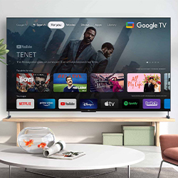A modern living room with a large flat-screen TV displaying Google TV interface. Movie selections like "Tenet" are visible, with a relaxed, tech-savvy vibe.