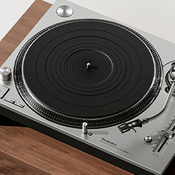 A vintage turntable on a wooden surface, featuring a black platter and silver tonearm. The design conveys a retro, nostalgic feel with precise detailing.