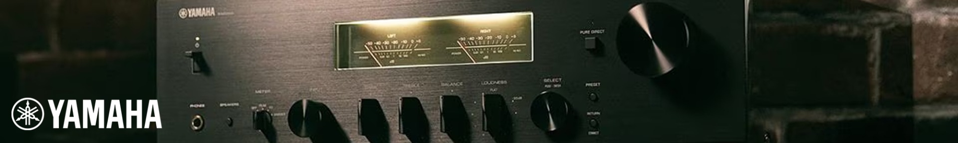 Close-up of a Yamaha stereo receiver with a classic design. Features include a lit display with analogue level meters, various knobs, and a sleek black finish, evoking a vintage, high-fidelity ambiance.