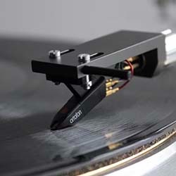 A black amplifier with knobs and buttons sits on a wooden console table in a modern room. 