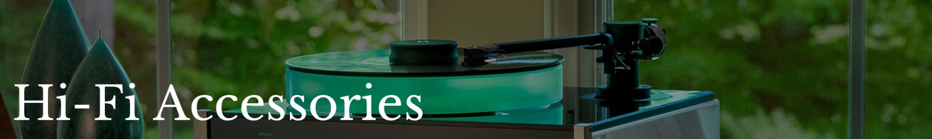 A modern turntable with a glowing green platter sits by a window, surrounded by lush greenery. The text "Hi-Fi Accessories" overlays the serene scene.