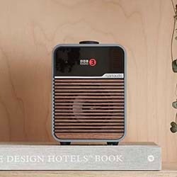 Vintage-style radio with wood accents and a modern touch sits atop a textured book. The setting is warm and minimalist, evoking nostalgia and elegance.