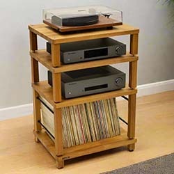 A sleek black audio component with a CD tray sits on a wooden cabinet against a neutral wall, conveying a minimalist and modern vibe.