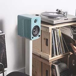 A smartphone playing music lies on stacked books beside headphones. The screen shows an ocean scene.