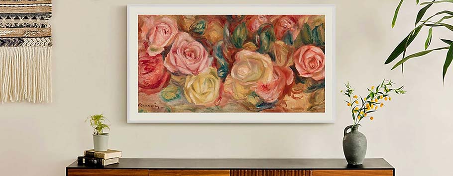 Framed painting of vibrant roses in red, pink, and yellow hues on a beige wall. Below, a wooden table with potted plants adds a serene touch.