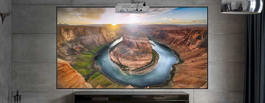 A large home theater screen displays a vivid image of Horseshoe Bend at sunset. The warm, golden light enhances the red rocks and winding river.
