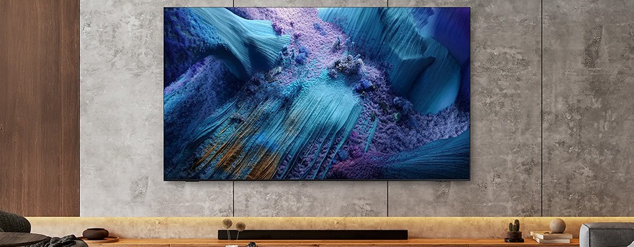 A large flat-screen TV displaying a vivid abstract image with blue and purple textures hangs on a modern concrete wall above a minimalist shelf.