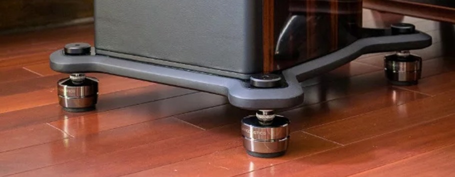 Audio equipment with isolation feet on a wooden floor. The sleek design of the feet elevates the device slightly.