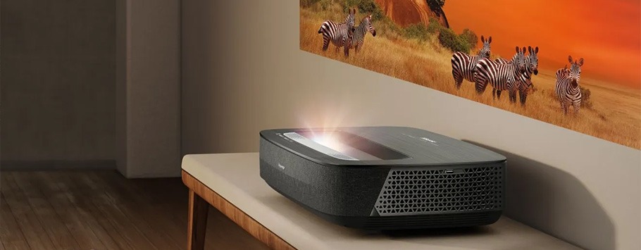 A sleek, black projector beams a vibrant image of zebras on a sunny savannah onto a wall, creating a lively and immersive viewing experience.