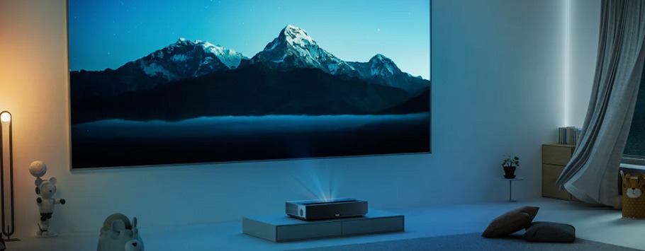 A cozy room with a large projector screen displaying snowy mountains under a clear blue sky. Soft lighting, cushions on the floor, modern and serene.