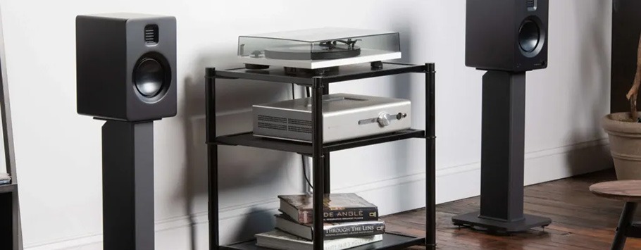 Black Speaker stands with bookshelf speakers on top in a living room space.