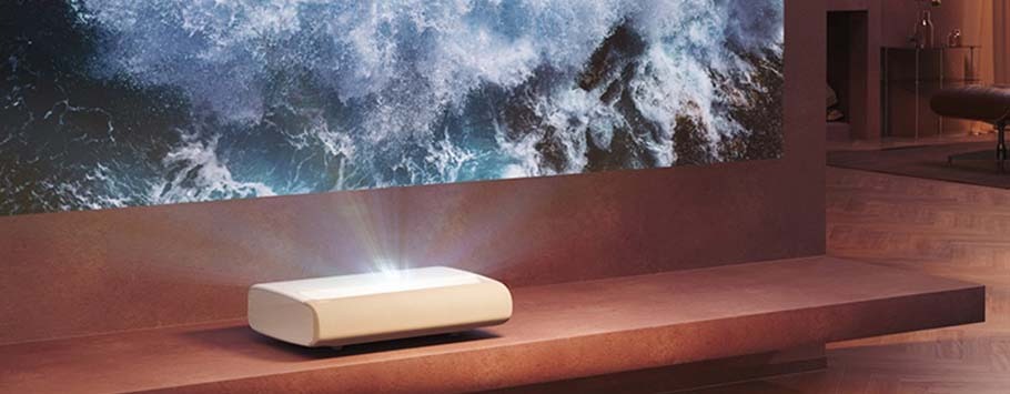 A sleek white projector casts a vivid ocean wave image on a wall in a modern, stylish room, creating a dynamic and immersive atmosphere.
